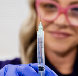 A provider with blue gloves holds up a syringe for sclerotherapy near New Albany, OH